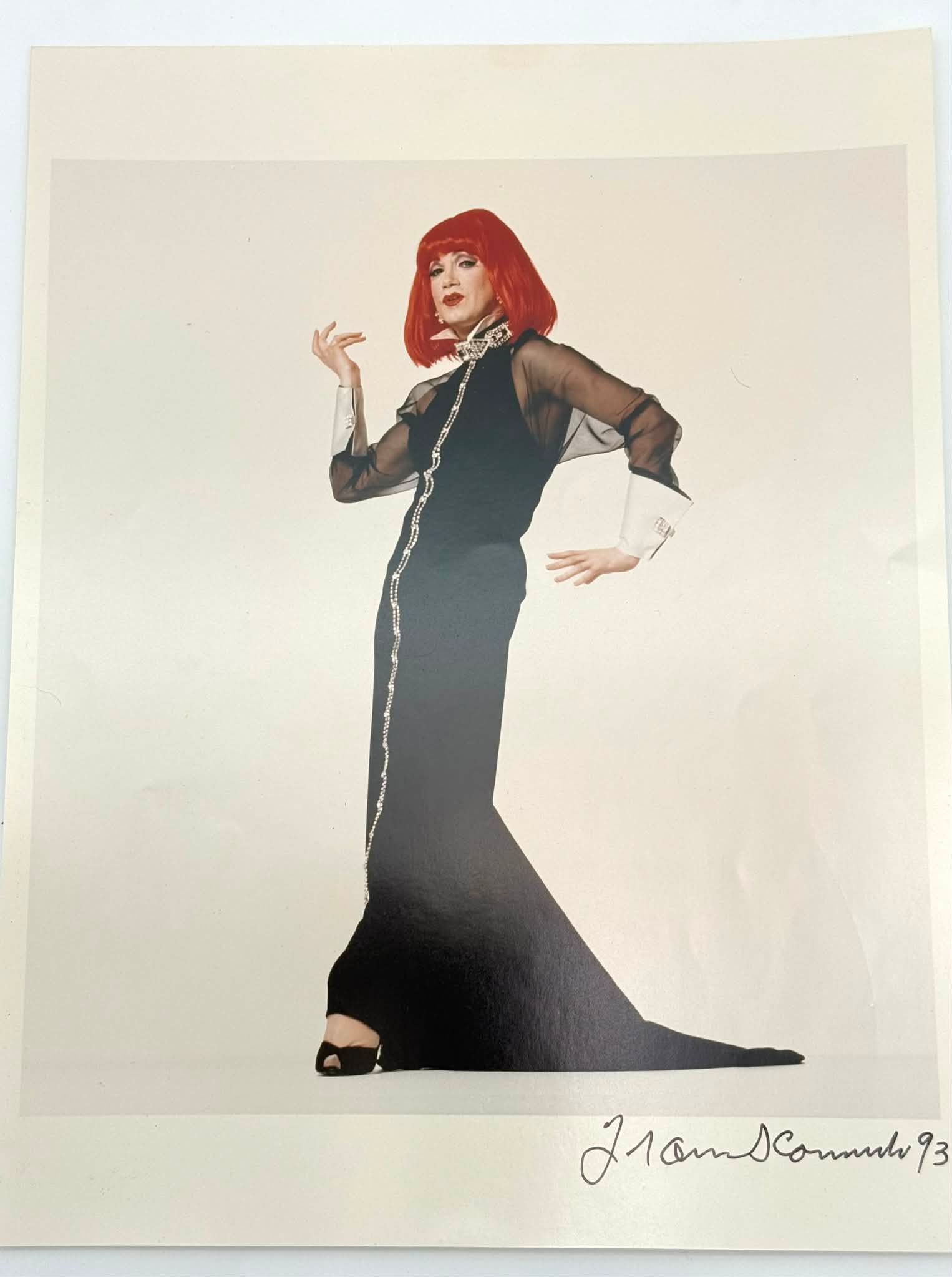 Francesco Scavullo Photograph “Red Wig” Signed 1993, Fashion Portrait: Color photograph titled “Red Wig” by Francesco Scavullo, featuring a stylized fashion portrait of a figure posed in an elegant black gown with a vivid red wig against a minimal studio backdrop