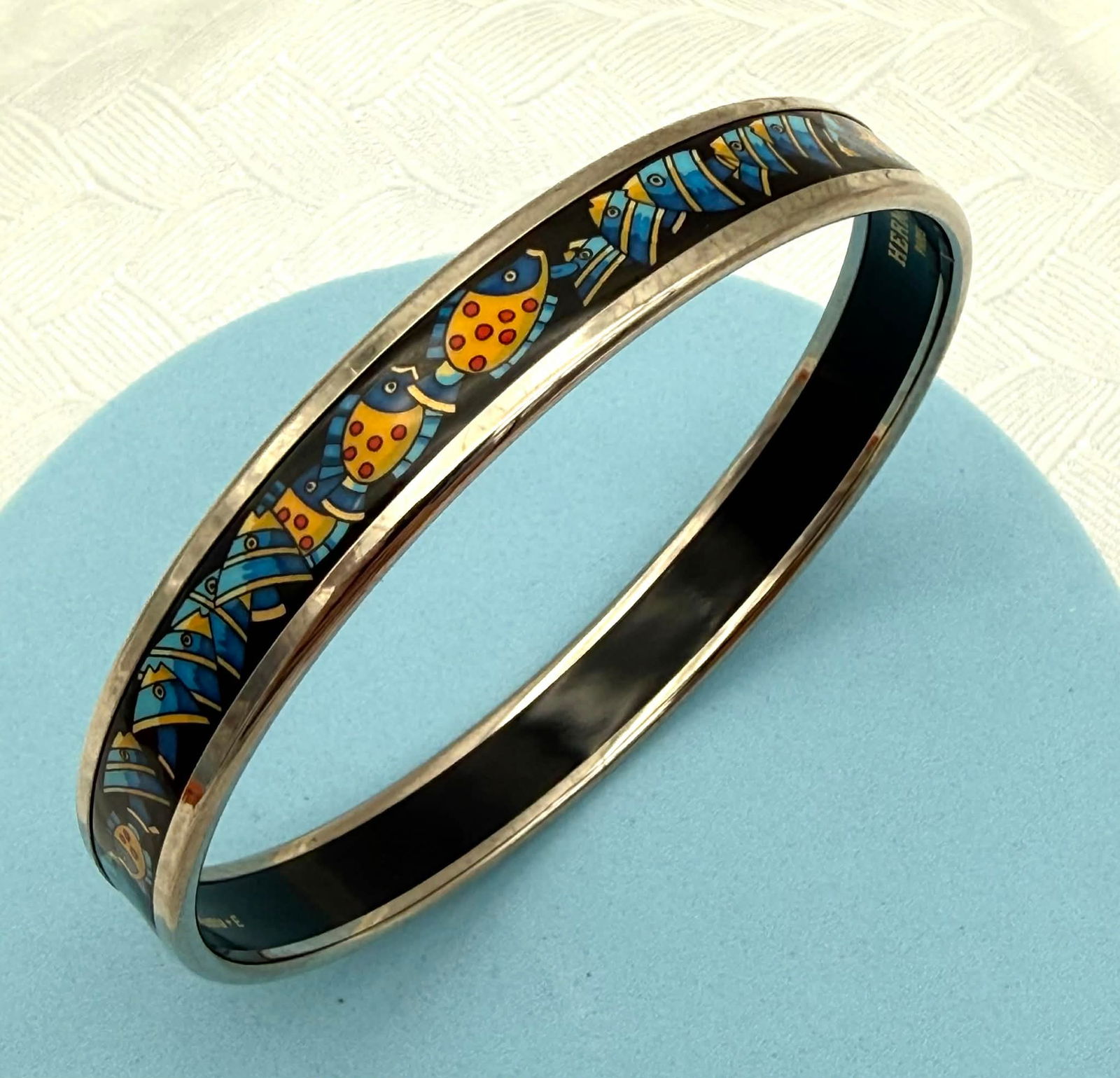 Hermès Paris Enamel Bangle Bracelet – Safari Animal Motif – Blue & Yellow – Made in Austria: Austria – With Box Elegant Hermès enamel bangle bracelet featuring a vibrant safari-inspired motif in rich blue, yellow, and black tones. The design displays stylized animal imagery and geometric p