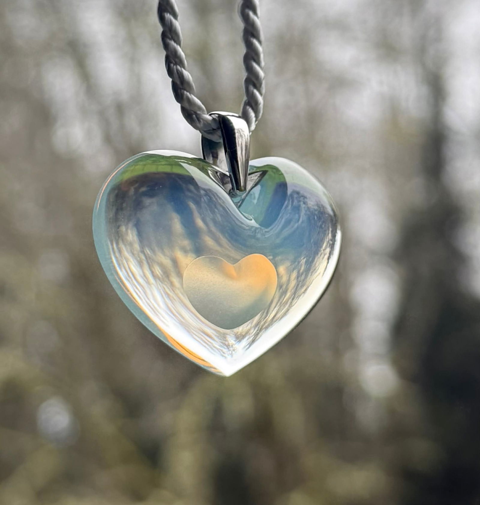 Lalique Crystal Heart Pendant Necklace with Box: Crystal heart pendant necklace by Lalique Paris. The pendant is crafted in opalescent crystal with a softly frosted interior heart motif, suspended from a white cord necklace with polished Lalique sig