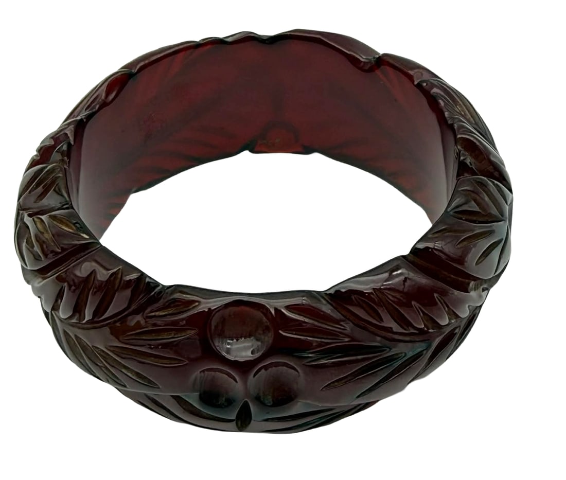 Carved Prystal Resin Bangle Bracelet, 1930s – New York Studio Collection: Carved translucent prystal resin bangle bracelet dating to the 1930s, featuring a richly sculpted foliate and geometric motif in deep oxblood and amber tones. The bracelet displays classic early plast