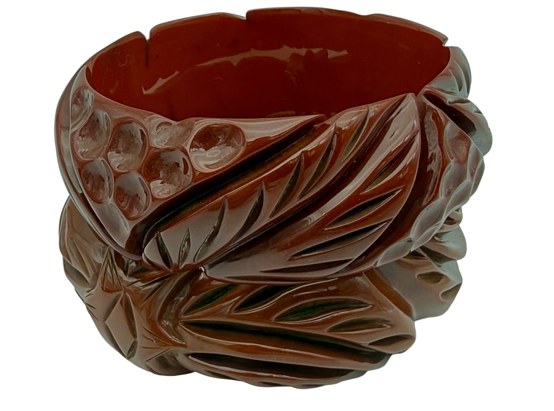 Two Carved Bakelite Bangle Bracelets, Dot & Foliate Motifs, 1930s–1940s – New York Studio: A pair of vintage carved Bakelite bangle bracelets dating to the 1930s–1940s, each featuring complementary yet distinct designs. One bracelet displays flowing foliate carving with elongated leaf for
