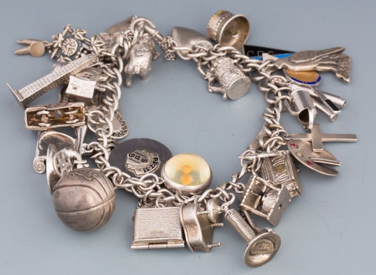 LOADED STERLING SILVER CHARM BRACELET: LOADED STERLING SILVER CHARM BRACELET Sterling silver charm bracelet with over 30 charms, including but not limited to polar bear, angel, Washington Monument, Trolley car (complete with moving conduct