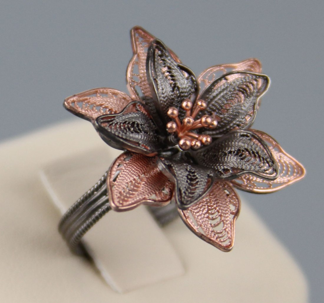 FLORAL STERLING RING W/ ROSE AND CHARCOAL FINISH: FLORAL STERLING RING W/ ROSE AND CHARCOAL FINISH Sterling flower fashion ring with 2 layers of petals. Each layer finished with either rose or charcoal color. Petals are defined by intricate sinuous s