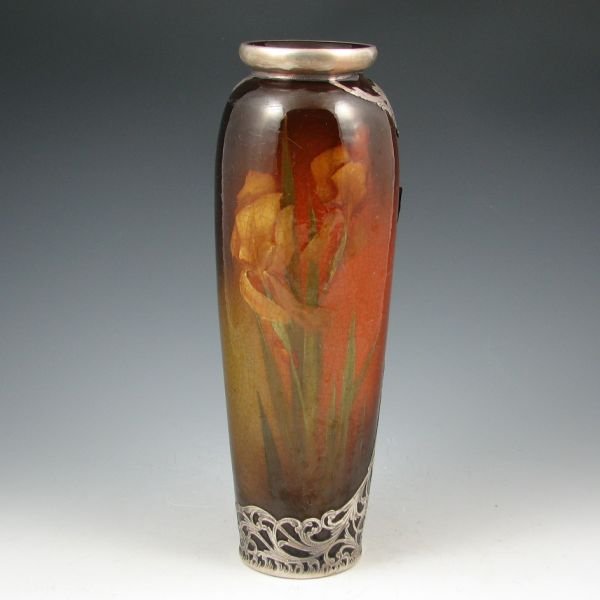 Owens Utopian 11 1/2" Silver Overlay Vase: Owens Utopian silver overlay vase with floral decoration under standard glaze. Marked JB Owens Utopian 878. The silver is marked STERLING. There is a broken and lost segment to the overlay on the back