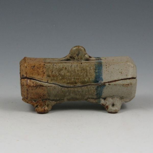 Walt Schmidt Lidded Trinket Box: Walt Schmidt lidded trinket box with feet. Marked with impressed and incised marks. There are some small nicks and chips to the rim of the box and lid. 4 1/4" long by 2 1/2" tall.