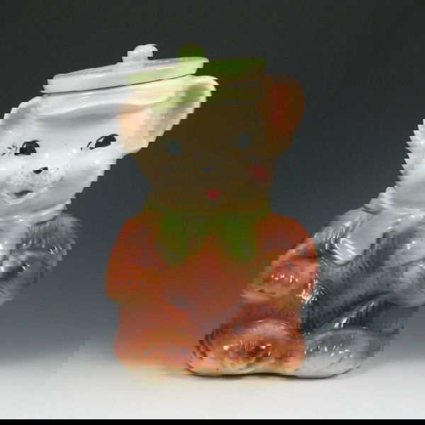 American Bisque Bear w/ Green Hat Cookie Jar: American Bisque bear in a green hat cookie jar. Marked USA. There is a chip to the inside of the lid's rim, which may be in the making. 11 3/4" tall.