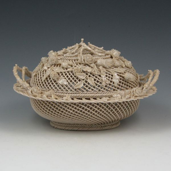 Belleek Three-Strand Covered Basket (1865-1889): Belleek three-strand covered oval basket with superior applied decoration. Marked Belleek on a single pad (circa 1865-1889). Excellent condition with no noticeable loss or damage. 8 1/2" wide by 5" ta