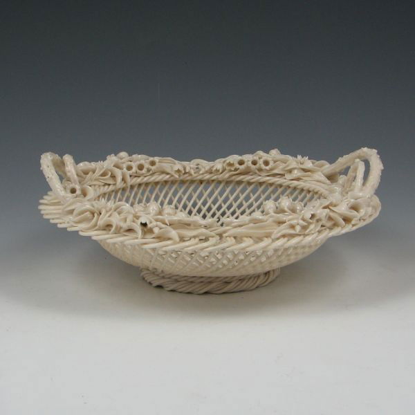 Belleek Three-Strand Footed Basket (1890-1920): Belleek three-strand Lily of the Valley basket. Marked Belleek Co. Fermanagh on a single pad (circa 1890-1920). Minor loss to the applied decoration, which appears to be limited to one flower. 9 3/4"