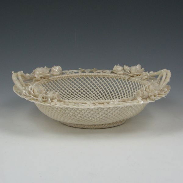 Belleek Four-Strand Floral Basket (1921-1954): Belleek four-strand floral basket with Mother of Pearl lustre. Marked Belleek Co. Fermanagh Ireland on a single pad (circa 1921-1954). Small area of repair to the rim and attached decoration. 10" wide