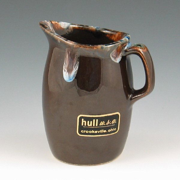 Hull House & Garden Oven Proof Creamer w/ Label : Hull House & Garden creamer in mirror brown with unusual blue drip trim. There is a Hull label on the body and the bottom is marked Hull Oven Proof USA. There is a scratch to the glaze near the label.
