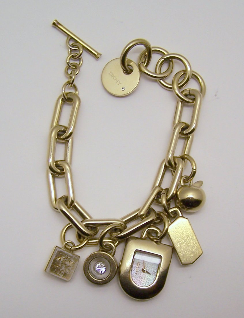DKNY gold tone charm bracelet watch: measures 7 7/8" long, crafted with 7/8" long to 1 1/2" long charms, weights 73.56 grams, signed DKNY , in good condition need battery, note 1 pof the charms need to be romeve other wise will be in gre