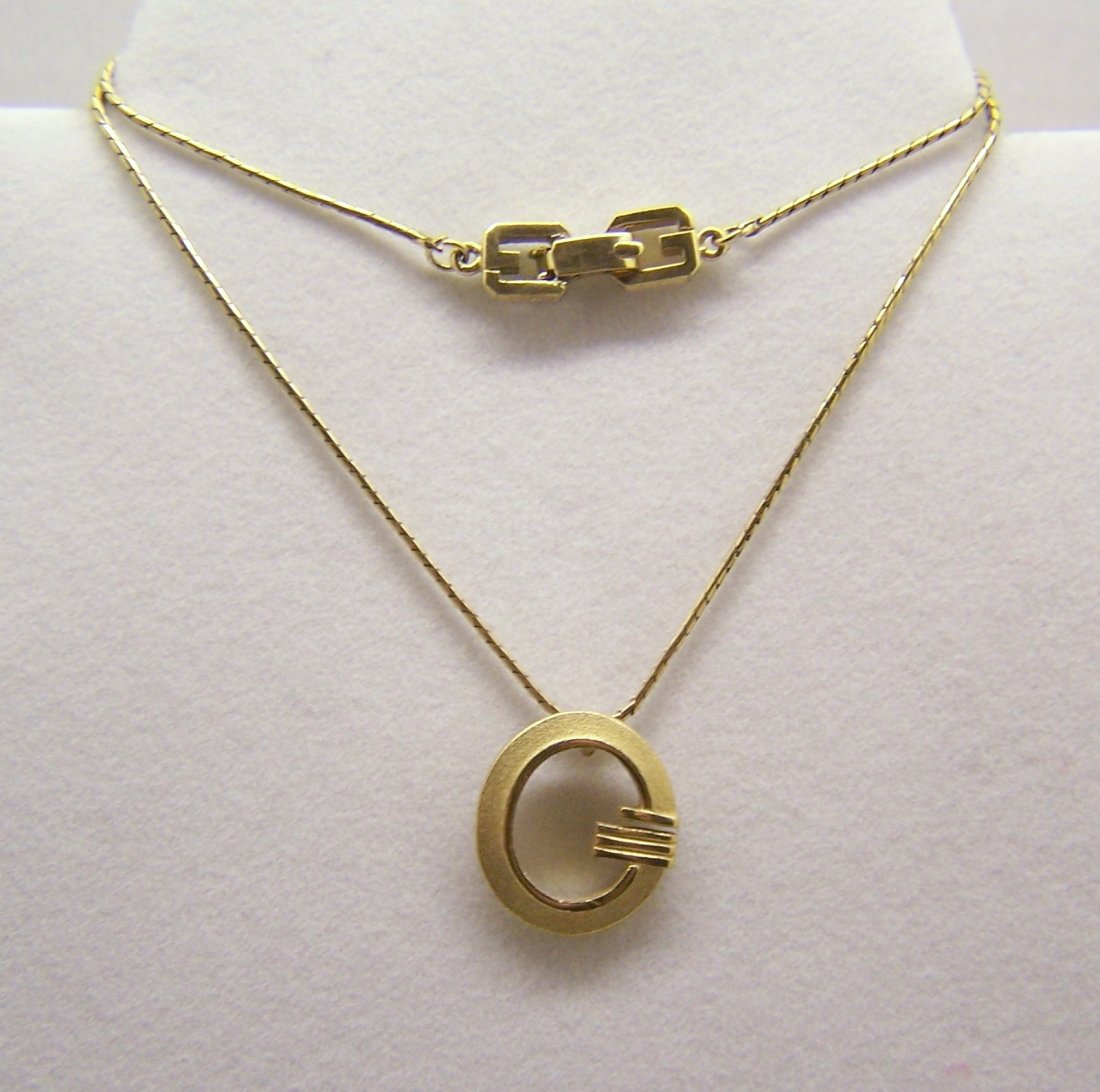Givenchy gold tone necklace: measures 16 1/4" long, the pendant measures 13/16" long by 11/16" wide, weights 6.95 grams, signed Givenchi new york-paris, in great condition