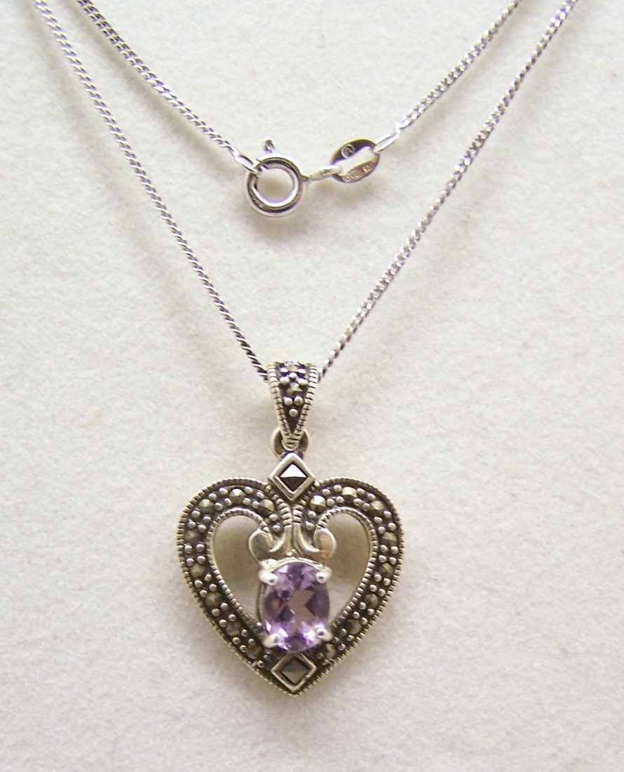 sterling silver amethyst marcasite necklace: pendant 1 1/8" long by 13/16" wide, crafted with 8x6mm amethyst, the chain measures 18" long weights 6.2 grams, signed 925 A,in good condition