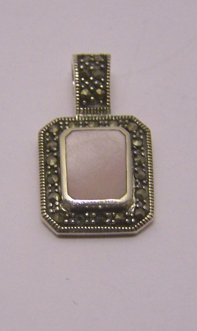 A sterling silver mother pearl marcasite pendant: measures 1" long by 9/16" wide, weights 3.6 grams, in good condition