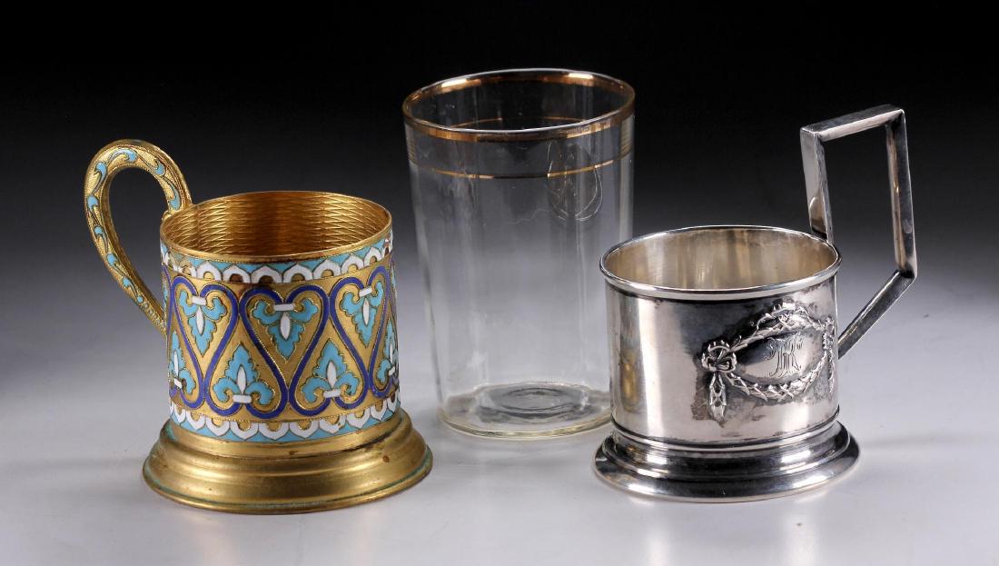 A Latvian Silver & Russian Gilt Metal Tea Cup Holder: The Latvian silver cup holder marked 875 with a glass tea cup. The Russian gilt enameled metal marked in cyrillic metal and makers mark. Silver weight: 4.55 ozt. Weight: 7/8 lbs. Condition: Minor enam