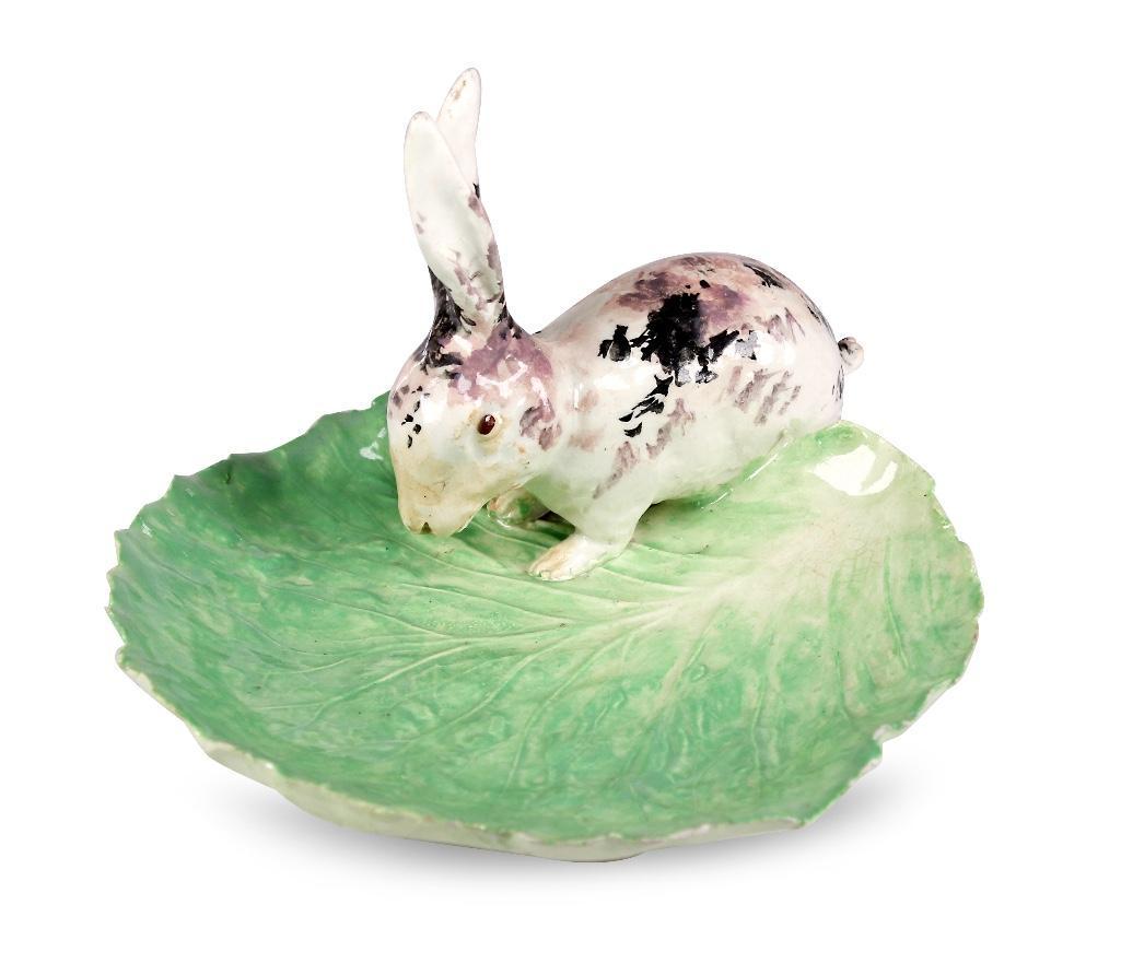 Early 20th C. Majolica Rabbit on Cabbage Leaf: The primitive glazed rabbit with upraised ears, standing on a cabbage leaf. Unmarked. H: 4 3/4; W: 7; D: 7 3/4 inches. Shipping weight: 1 lb Condition: Good