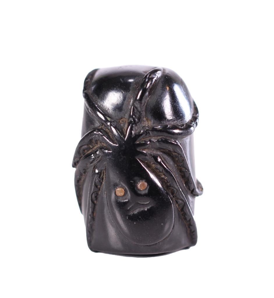 Japanes Edo Period Carved Ebony Octopus Netsuke: The cylindrical cup form carved ebony netsuke carved in relief depicting an octopus with inset staghorn eyes. The backside with single himotoshi with silver mount. Unmarked. Height: 1 1/2 inches; diam