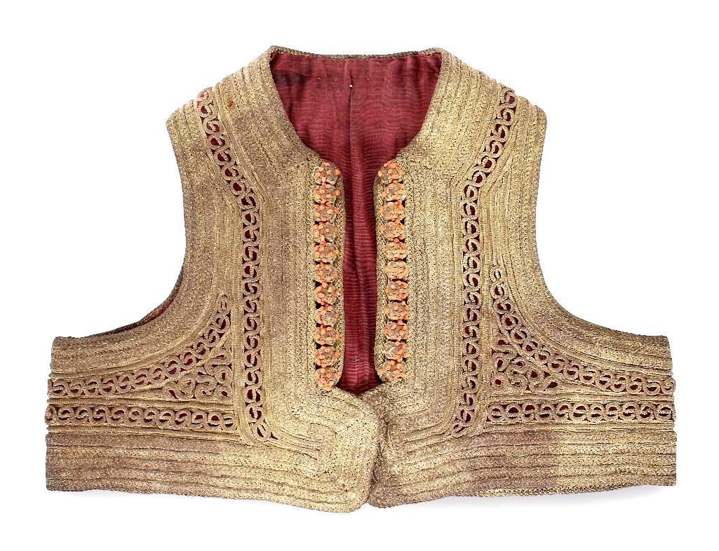 Southeast Asian Childs Gold Thread Vest: Childs vest with heavy gold metal thread embroidery and coral bead details. H. 11 1/8in; W. 15 1/8 in Shipping Weight: 2lb