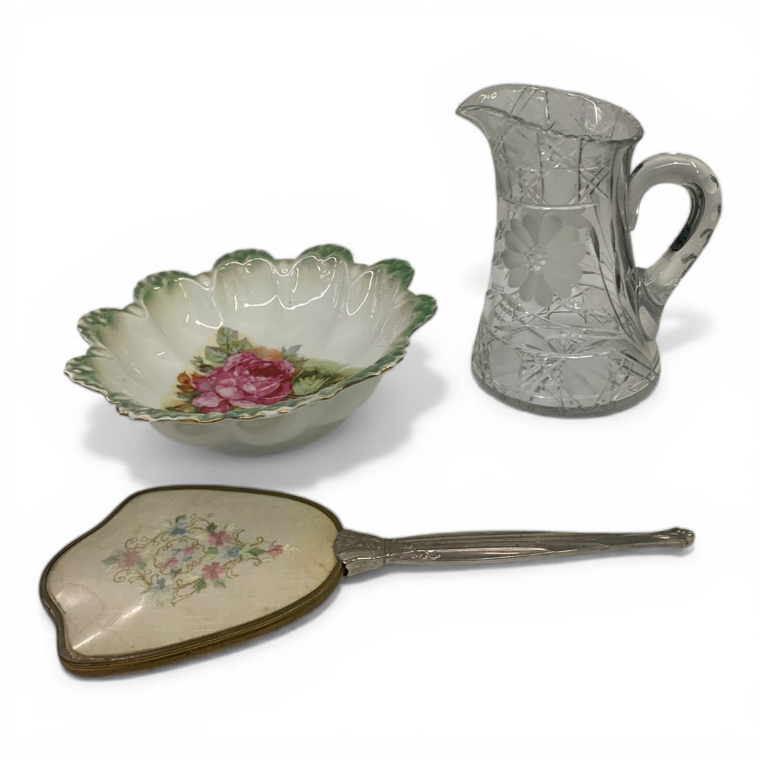 Cut Glass Pitcher, Porcelain Bowl & Hand Mirror: Cut Glass Pitcher, 8.5" Tall. Shows Wome Wear On Rim. Hand Mirror With Needlework Insert, 14.25" Long. Beveled Glass, Silver Plate Handle. Floral Needlework. Floral Porcelain Deep Bowl. 10.75"