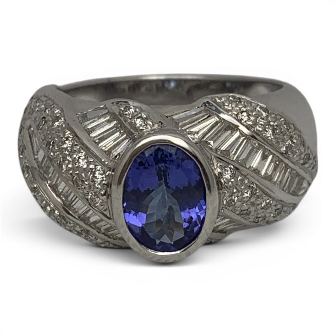 18k White Gold Diamond & Tanzanite Cocktail Ring: 18k White Gold Cocktail Ring Featuring 1 Center Set Oval Cut Tanzanite Gemstone Surrouneded By 29 Tapered Baquette Cut Diamonds & 52 Round Cut Diamonds.Marked: 18k - Size 6 - 5.6 DwtGemstones Tested W