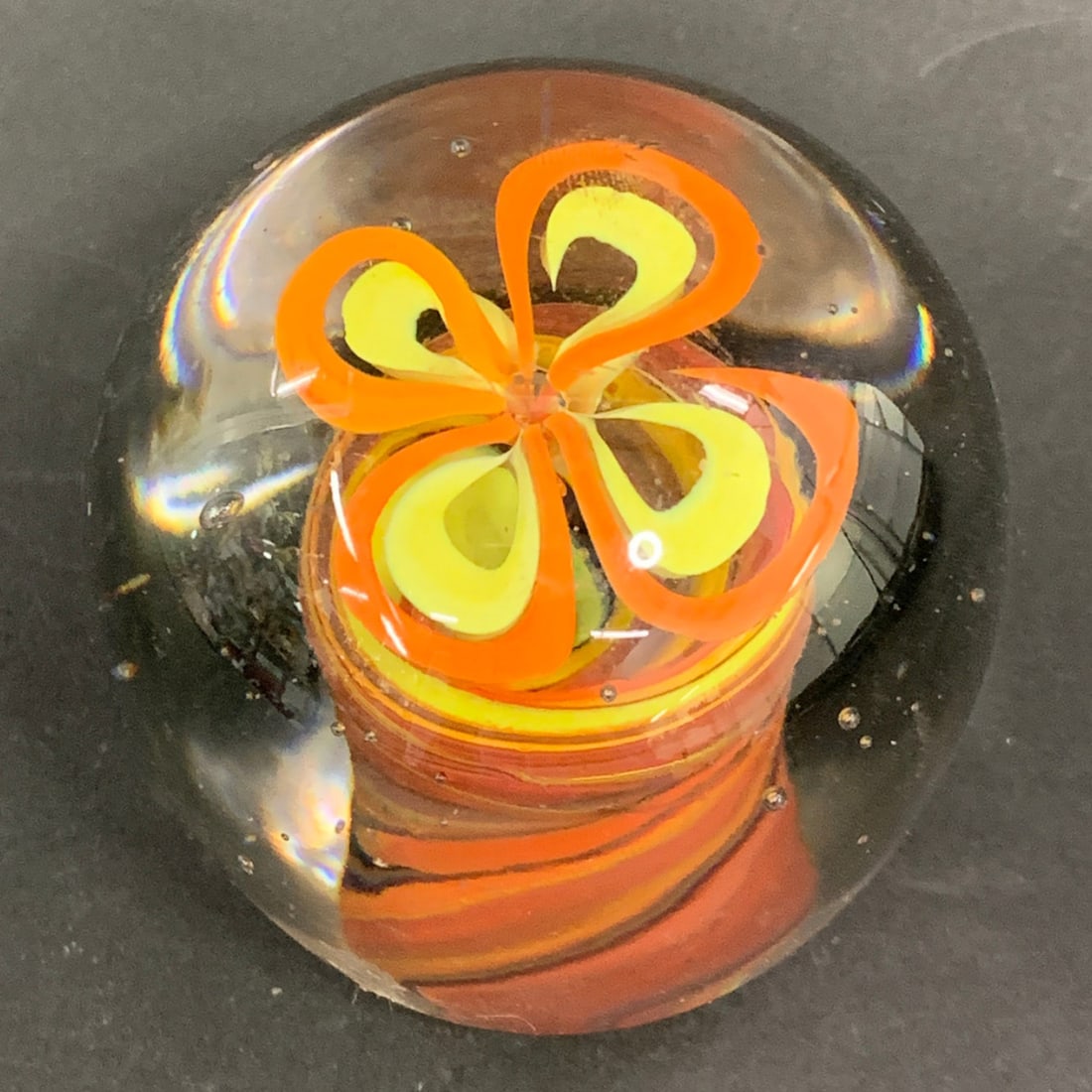 Hand Blown Art Glass Paperweight: Hand Blown Art Glass Paperweight Featuring A Multicolored Spiraled Base With A Yellow And Orange Flower Design2 1/2" Tall