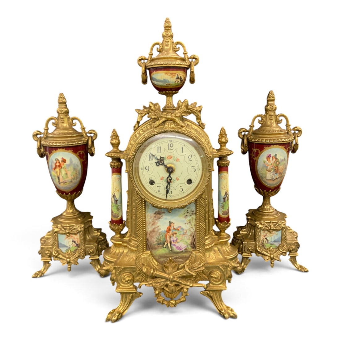 3pc. Lancini & Franz Hermle Mantel Clock Set: Vintage 3pc. Lancini & Franz Hermle Italian Porcelain Mantel Clock Garniture Set Featuring Ornate Gilt Brass Framing And Hand Painted Romantic Scene PanelsMarked On Movement: F H S, Germany, 130-0712 