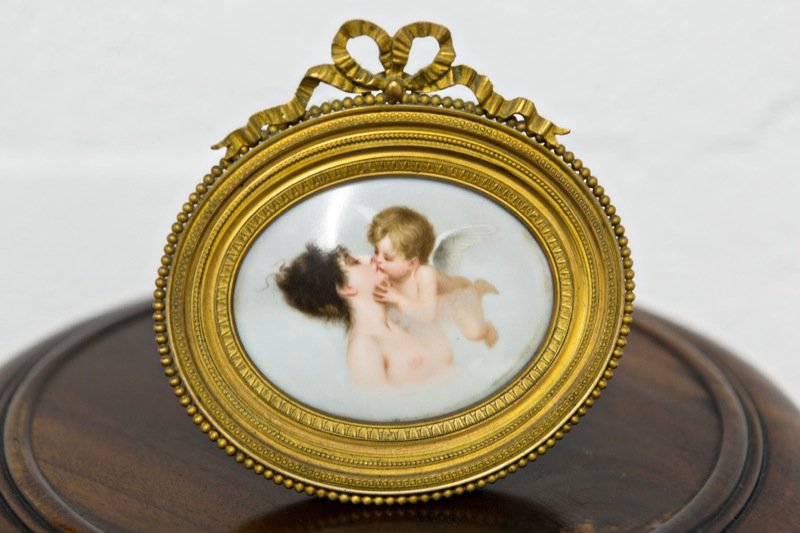 Hand Painted Limoges Plaque- Lady and Cherub: Hand painted Limoges plaque- Lady and cherub. 3"w x 2.5"h. Beautifully hand painted miniature Limoges plaque in a gilt frame crested with a ribbon. Marked for Claude Carpenet, Limoges. This lot is gua