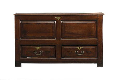 An 18th century elm mule chest: An 18th century elm mule chestThe hinged top with moulded edge opening to a plain interior with candle box, above fielded and cross-banded panels and two drawers, raised on extended stiles.131cm wide
