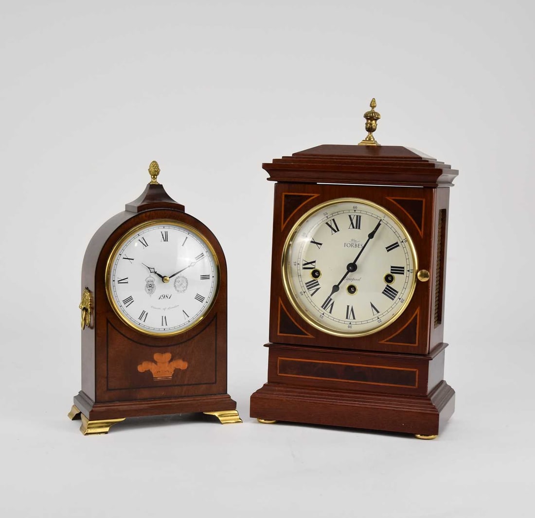 Two reproduction mantel clocks: Forbes of Liverpool and Comitti of London: Two reproduction mantel clocks Forbes of Liverpool: The Sudley Chamfer Top Bracket Clock, the mahogany case with brass urn finial, the 5.5 inch white enamel dial with Roman chapter and Arabic outer mi