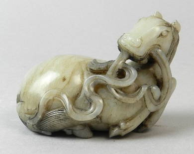 Halls Summer Collective Auction 21st August: A Chinese mottled white jade carving of a recumbent horse, realistically detailed with its head turned backwards, and with ribbons in its mouth, and draped all across the body, 9cm long, 6.5cm high.