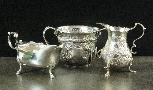 A Victorian silver porringer, Charles Stuart Harris,: A Victorian silver porringer, Charles Stuart Harris, London 1898, with half reeded embossed decoration, vacant cartouche and two scroll handles, 7.5cm high, together with a Newcastle silver cream boat