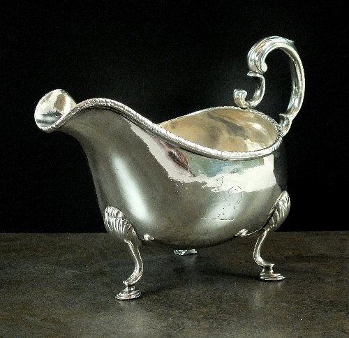 A George III Irish silver sauce boat, Matthew West,: A George III Irish silver sauce boat, Matthew West, Dublin 1781, the plain polished body, with rope twist rim, engraved crest and scroll handle, all raised on three stepped hoof feet, 12.5cm high, wei