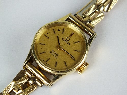 A lady's 14ct gold Omega Deville quartz wristwatch, the: A lady's 14ct gold Omega Deville quartz wristwatch, the champagne dial with black batons, with attached gold plated decorative bracelet