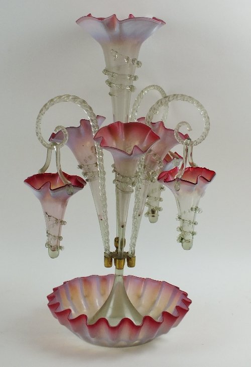 Fine Furniture, Euopean Ceramics & Works of Art: A Victorian cranberry and clear glass epergne, the large central stem supporting three trumpet shaped vases, surrounded by three glass candy canes supporting baskets, lobed circular base, 56cm high, s