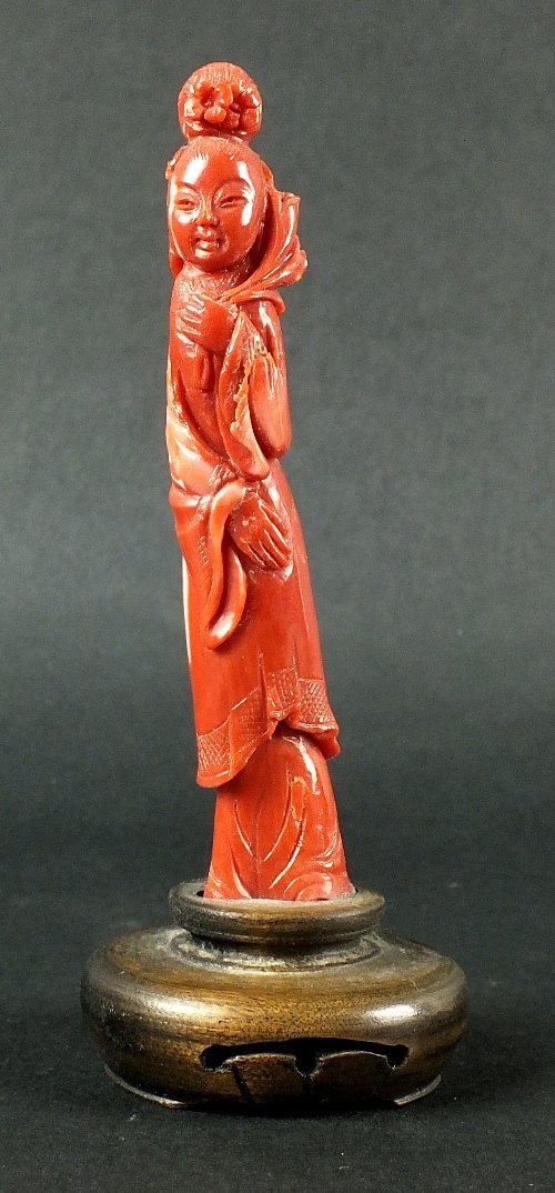A Chinese carved coral figure of Guanyin, 19th century,: A Chinese carved coral figure of Guanyin, 19th century, the slender figure modeled in long robes with flowers in her hair, holding a lingzhi sceptre in one hand, the coral of a deep pink colour with w