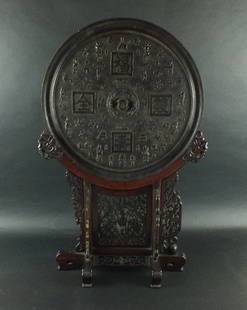 A large Chinese bronze mirror in archaic style and: A large Chinese bronze mirror in archaic style and hardwood floor stand, first half 20th century, the circular mirror polished to one side, the reverse embossed with four auspicious Chinese