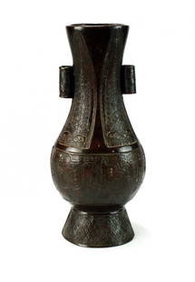 A Chinese bronze arrow vase, possibly Ming, of  slender: A Chinese bronze arrow vase, possibly Ming, of slender pear form with twin tubular handles and raised on a conical base, cast with archaistic forms, 21cm high.