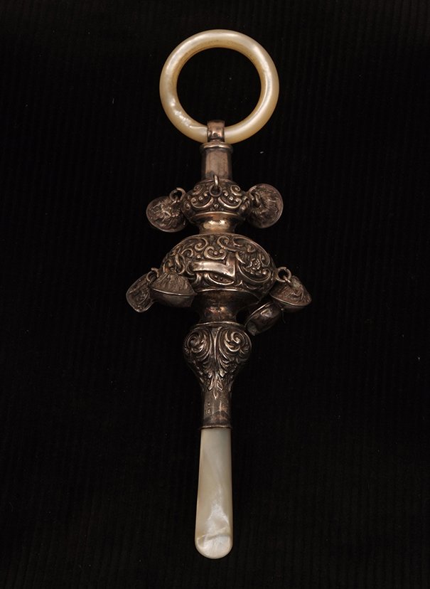 An Edwardian silver and mother of pearl baby's rattle: An Edwardian silver and mother of pearl baby's rattle with repousse decoration and mother of pearl teething ring, 4 bells lacking, Birmingham 1906, 6.5in overall length.