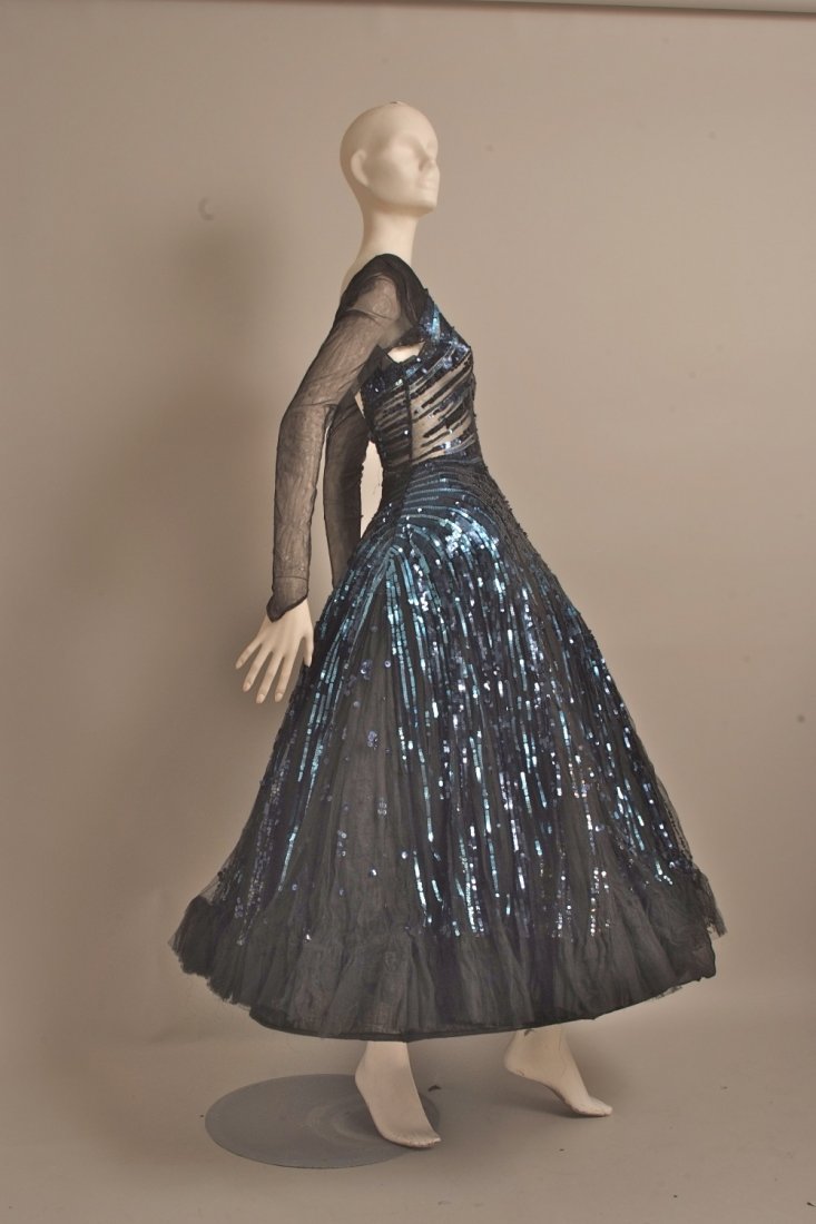 A stunning 1940's tulle and sequined ball gown. This: A stunning 1940's tulle and sequined ball gown. This beautiful full skirted tulle dress is covered in sapphire and dark blue sequins, with long tulle sleeves a low cut back with a jewel in the centre.