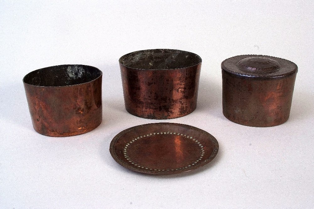 A John Pearson Arts & Crafts copper circular plate,: A John Pearson Arts & Crafts copper circular plate, beaded hand beaten border, signed JP to base, 13cm, together with three Arts & Crafts copper pots bearing mark Harrods, one with lid, (4)