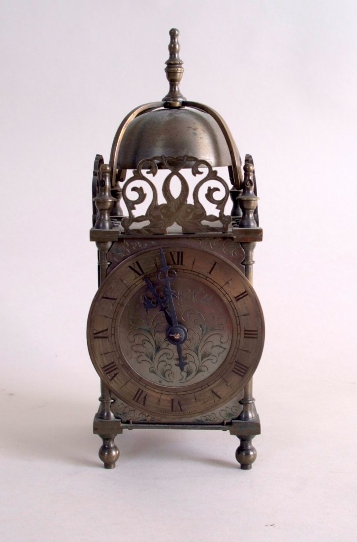 A late 19th/early 20th century brass lantern clock, by: A late 19th/early 20th century brass lantern clock, by Mappin & Webb, circa 1900, pierced gallery depiting fish to three sides of the bell top, the dial with Roman numerals to chapter ring, hinged doo