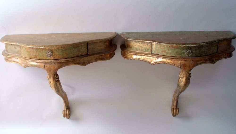 A pair of Italian giltwood small console tables, with D: A pair of Italian giltwood small console tables, with D shaped tops, above a drawer, on a single scroll support, 51cmW
