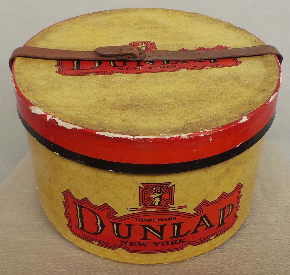 A vintage card and leather strap hat box printed: A vintage card and leather strap hat box printed 'Dunlap' New York in fair condition