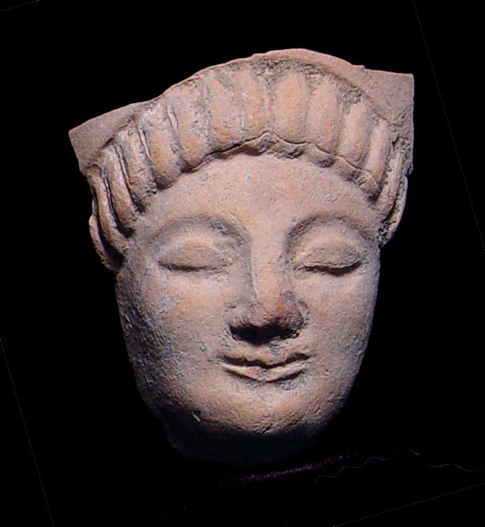 ARCHAIC GREEK VOTIVE TERRA COTTA GODDESS: AN ARCHAIC GREEK VOTIVE TERRA COTTA GODDESS. c. 4th century BC. The Korai style figure with long braided hair. 2 x 2.25 inches. Good example with good detail and remains of white pigment. Provenance: 