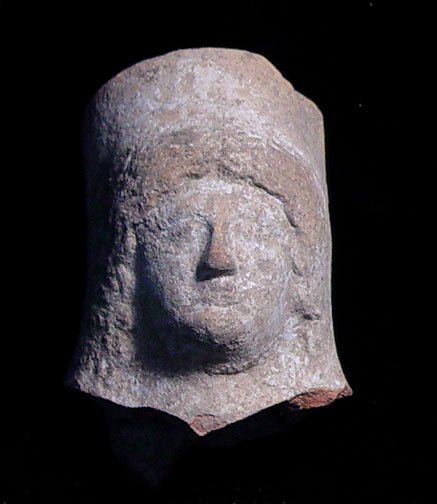 ARCHAIC GREEK VOTIVE TERRA COTTA GODDESS: AN ARCHAIC GREEK VOTIVE TERRA COTTA GODDESS. c. 4th century BC. The Korai style figure with long braided hair and wearing a polos on her head. 1.5 x 2.25 inches. Good example with good detail (better 