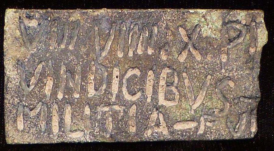 BRONZE PLAQUE WITH LATIN INSCRIPTION: LATIN BRONZE PLAQUE WITH INSCRIPTION, Uncertain age, possibly Roman. 7 x 3.5 cm. With inscription on both sides reading VIII.VIIII.X.PI VINDICIBVS - √MILITIA - PVI IMP CAES.G IVLIVS VERVS MAXIMI