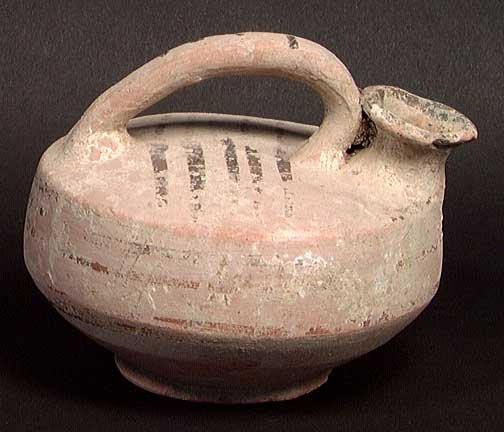 ELEGANT DAUNIAN GREEK ASKOS: SCARCE DAUNIAN GREEK ASKOS, c. 4th-3rd century BC. Black glazed designs on cream ground. 5". Nice condition and rare. A beautiful elegant form with impressive forward sweeping handle. Provenance: An e
