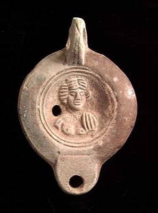 ROMAN FIGURAL OIL LAMP: ROMAN TERRA COTTA FIGURAL OIL LAMP, ca. 1st-2nd century AD. The lamp with a high profile facing bust with cloak over one shoulder on the discus. 4.3 inches. Maker's signature MNOVIVSI on