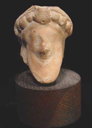 ROMAN ARCHAIZING HEAD OF DIONYSOS: ROMAN ARCHAIZING HEAD OF DIONYSOS, c. 1st-2nd century AD. The god depicted with garlanded hair and long spade beard. 2 x 2.5 inches. On custom oak stand. From the collection of an American artist livi