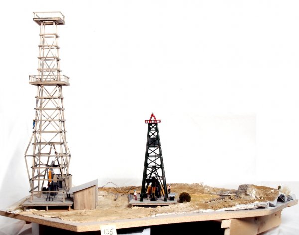 Oil well oil pumping derrick diorama/scene: Oil well oil pumping derrick diorama/scene that was mounted and used in an O gauge train layout. This is constructed of 3/4 inch particle board with a 1X4 framing. Wiring underneath. Large oil well me